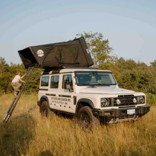White SUV with a go overland expedition mini rooftop tent in a grassy field