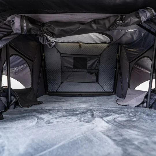 Interior of a gray rooftop tent camping tent with quilted floor and zippers.