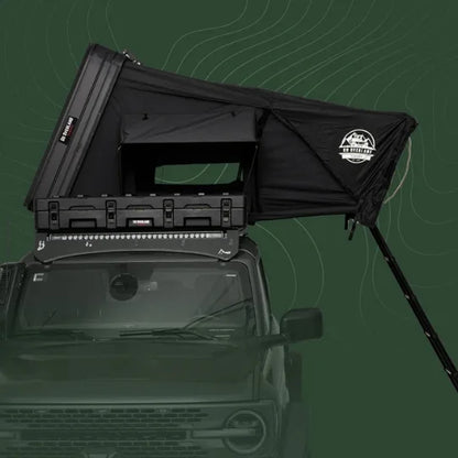 Black roof top tent attached to a vehicle with a green background