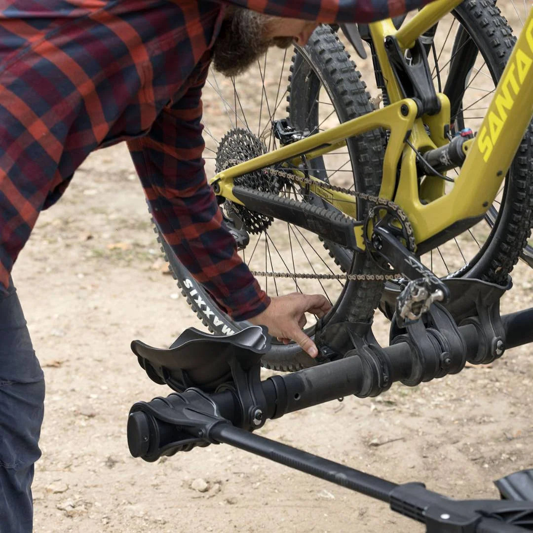 Person mounting a bike onto the Kuat Transfer V2 rack outdoors