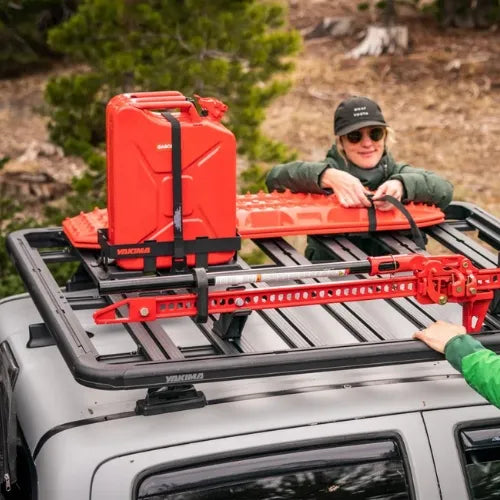 Person securing red roof racks on a vehicle with a scenic background