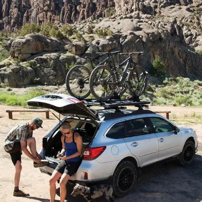 Two people with a car equipped with bike racks in a desert setting