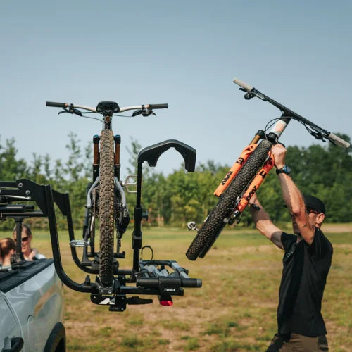 MOS UpLift™ Universal Lift Assist Rack System installed on a car with cottage in the background and with someone loading bikes on to it