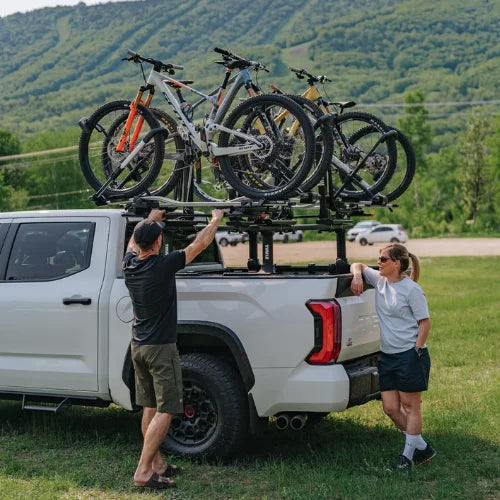 MOS UpLift™ Universal Lift Assist Rack System installed on a truck bed with trees in the background and with someone loading bikes on it
