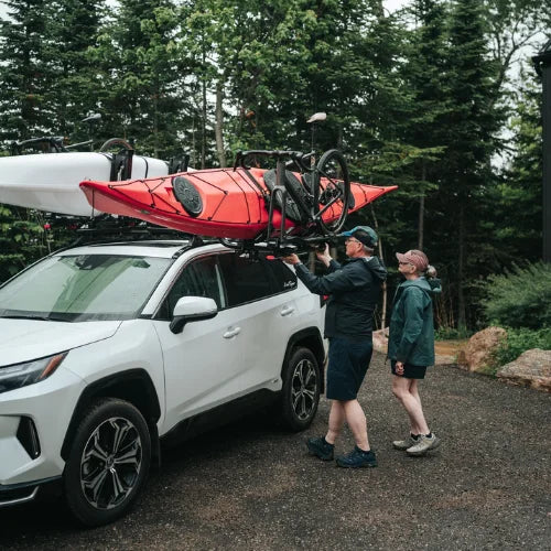 MOS UpLift™ Universal Lift Assist Rack System installed on a suv with trees in the background and with someone loading kayak and bike which is tilted down