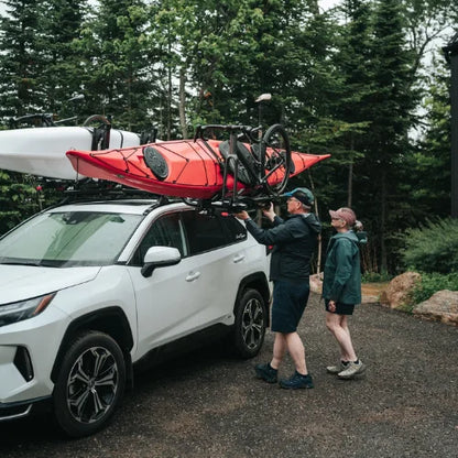 MOS UpLift™ Universal Lift Assist Rack System installed on a suv with trees in the background and with someone loading kayak and bike which is tilted down