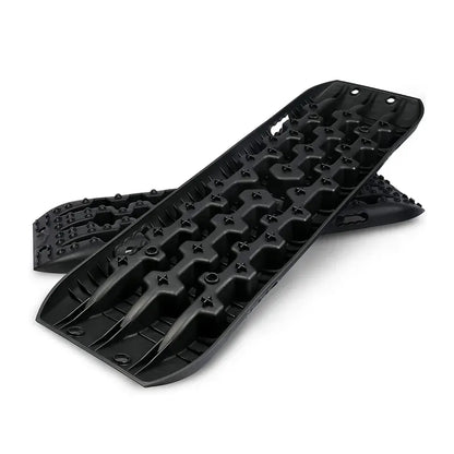 Pair of black overlanding recovery traction boards stacked at an angle, showing aggressive cleats