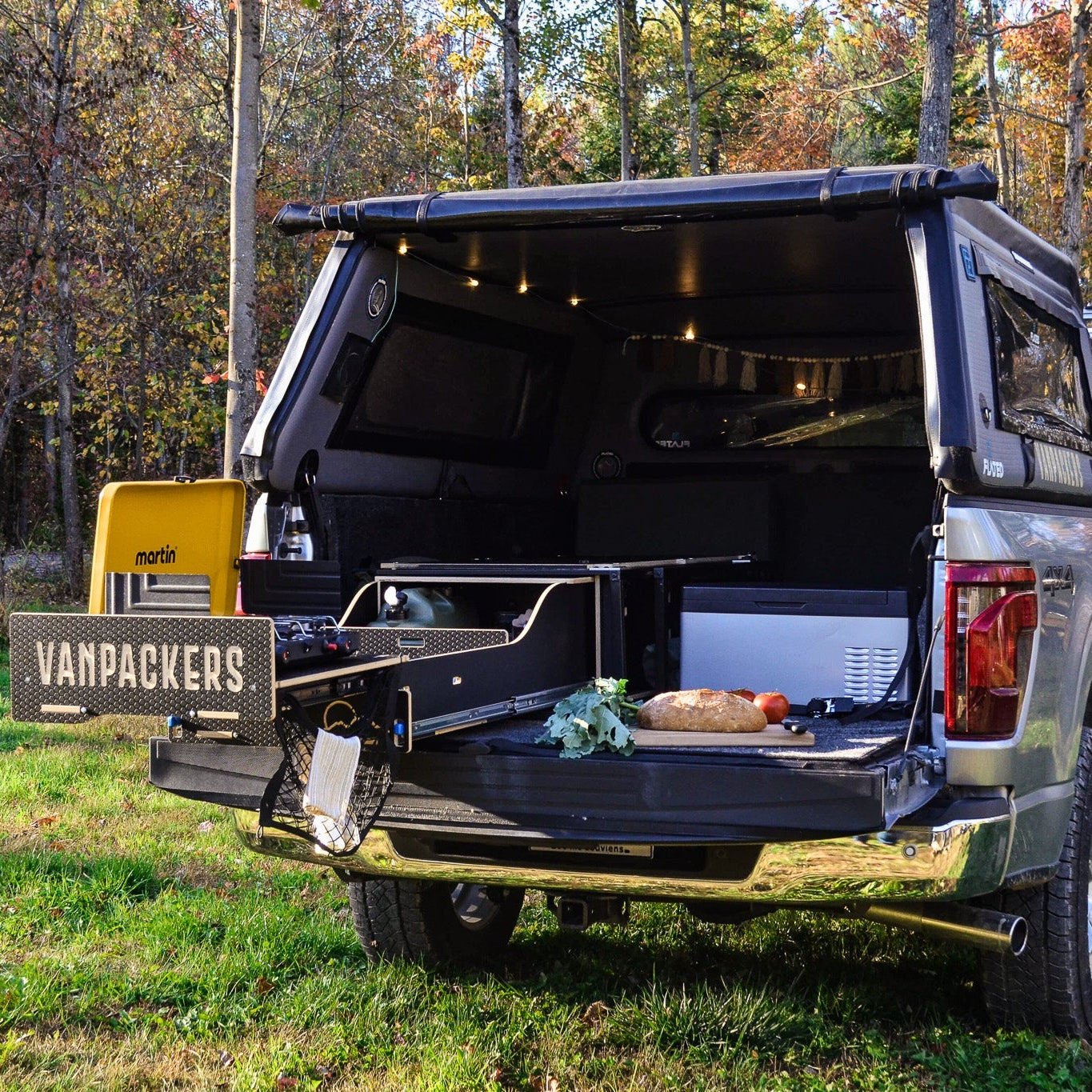 truck with open cargo area in a forest setting, featuring Vanpackers branding.