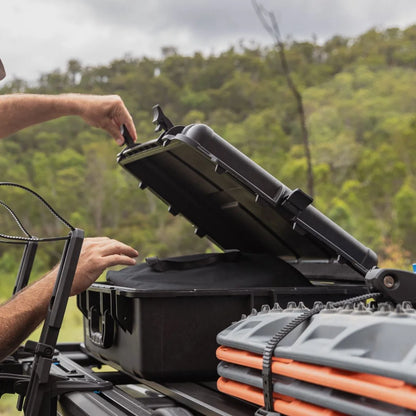Person loading equipment into a Rhino-Rack Cargo Case on vehicle roof.