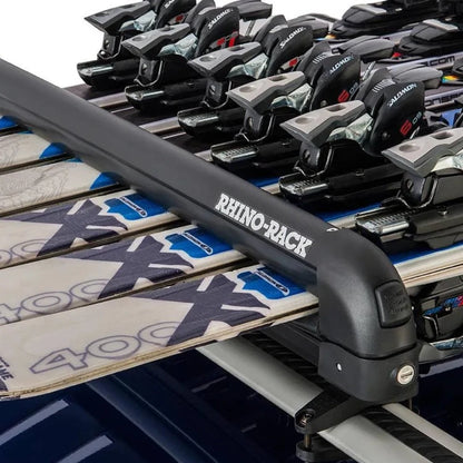 Angled side view of multiple skis held in a Rhino-Rack carrier on top of a roof rack system.