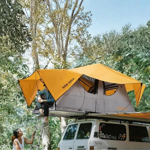 Van with a san hima alpine rooftop tent set up in a forested area