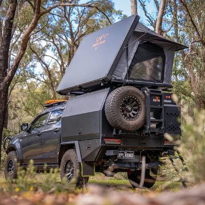Black off-road vehicle with a unfolded san hima kalbarri side gen 2 rooftop tent in a forest setting