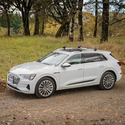 White SUV parked on a dirt road with trees in the background