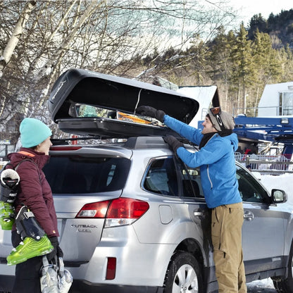Two people loading winter gear into an open SportRack Horizon Alpine on top of an SUV.