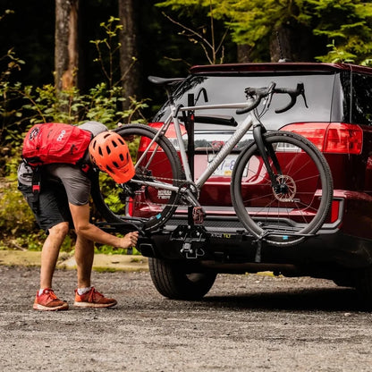 Person attaching bicycle to Swagman XTC2 Tilt at the back of a red car. 