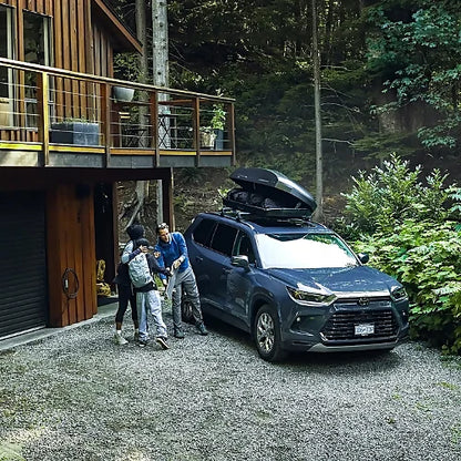 Family packing SUV with Thule Force 3 M rooftop cargo box outside forest cabin
