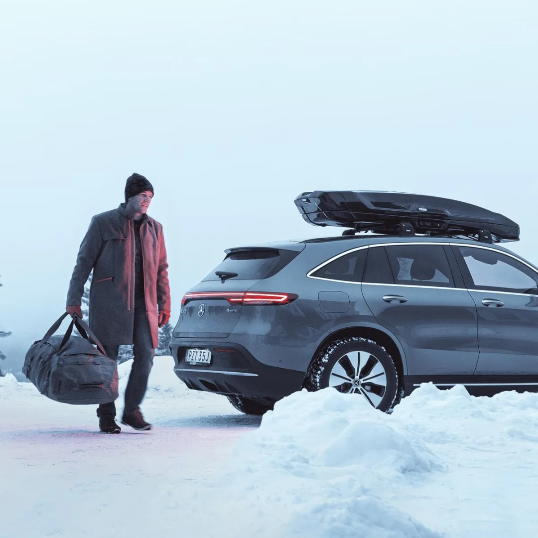 Man standing next to a snowy car with Thule Vector Alpine on the roof