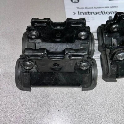 Black plastic components on a gray surface with instructions in the background