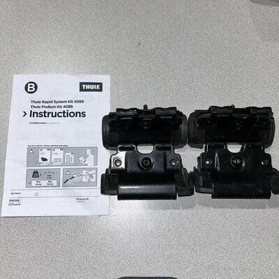 Two black Thule podiums with an instruction sheet on a gray surface