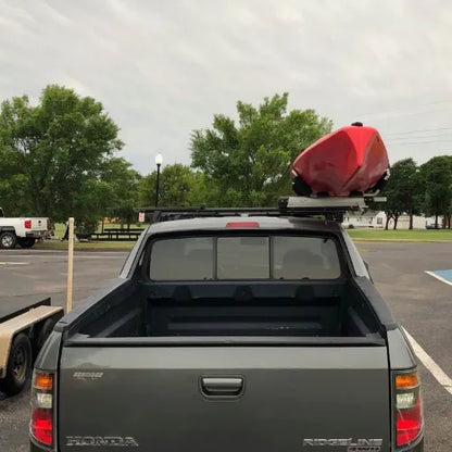 Thule Hullavator Pro  Gray Honda truck with a red kayak on a roof rack in a parking lot.