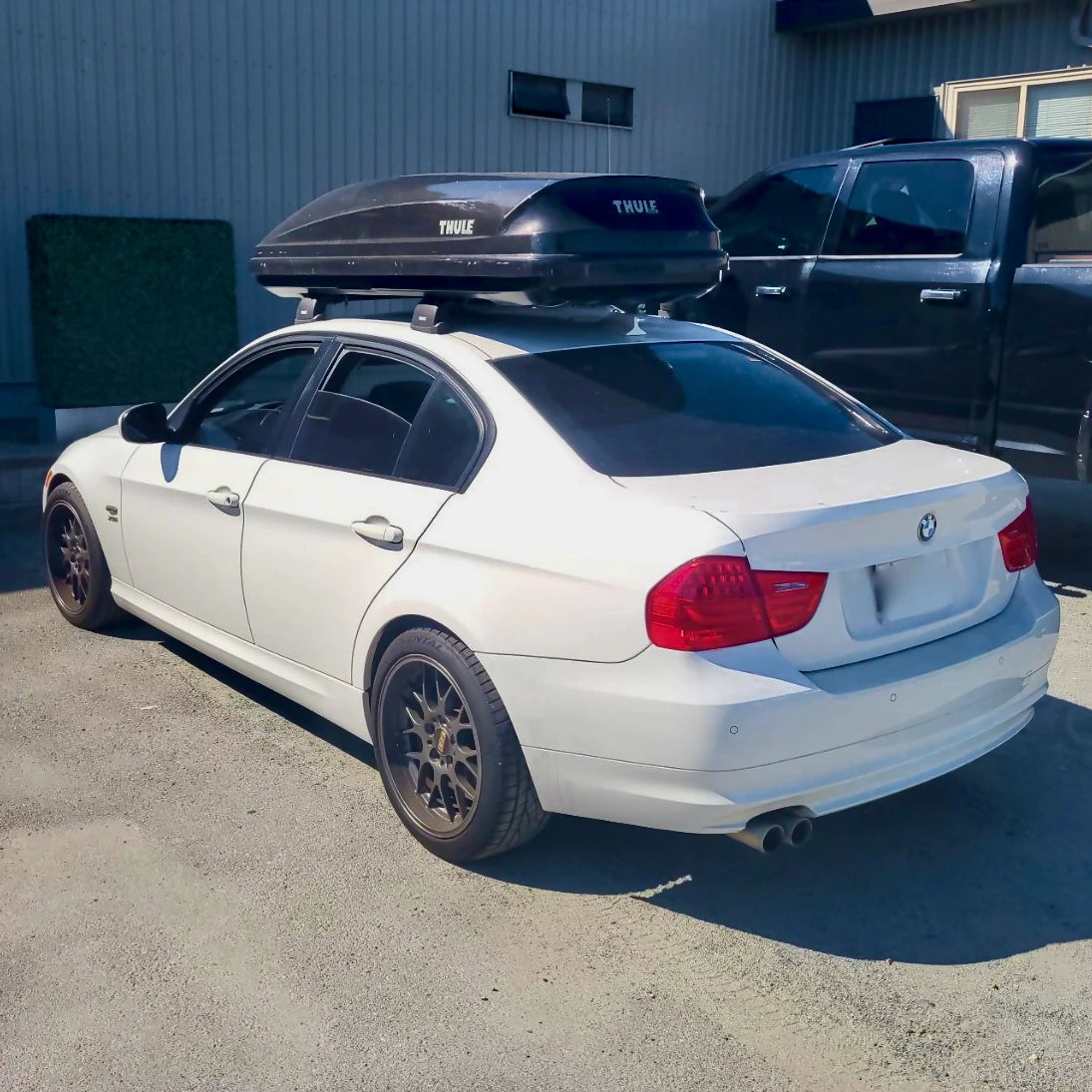 Thule Pulse cargo box installed on a white BMW parked outside a building.