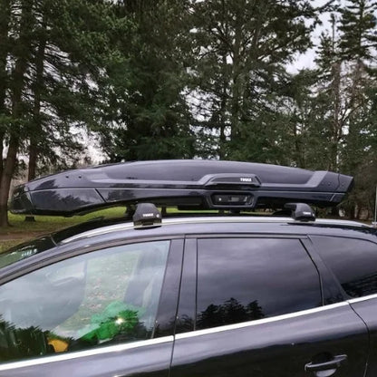 Car with a black roof rack system parked in a forested area