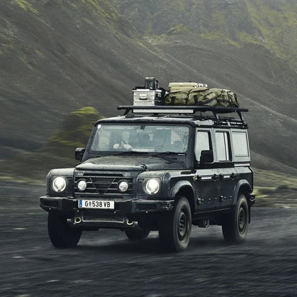  Land Rover with rooftop Caprock Platform carrying gear while driving through rugged terrain.