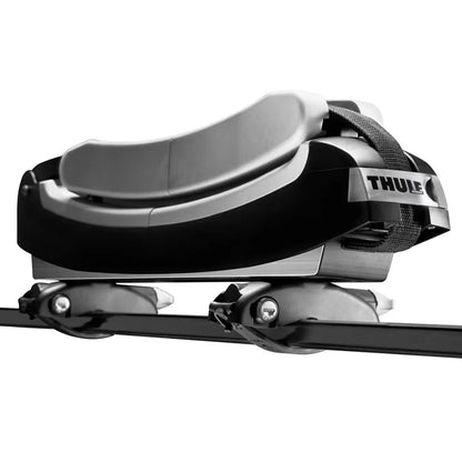 Close-up of Thule surfboard carrier showing padded cradle and securing strap mounted on a roof rack