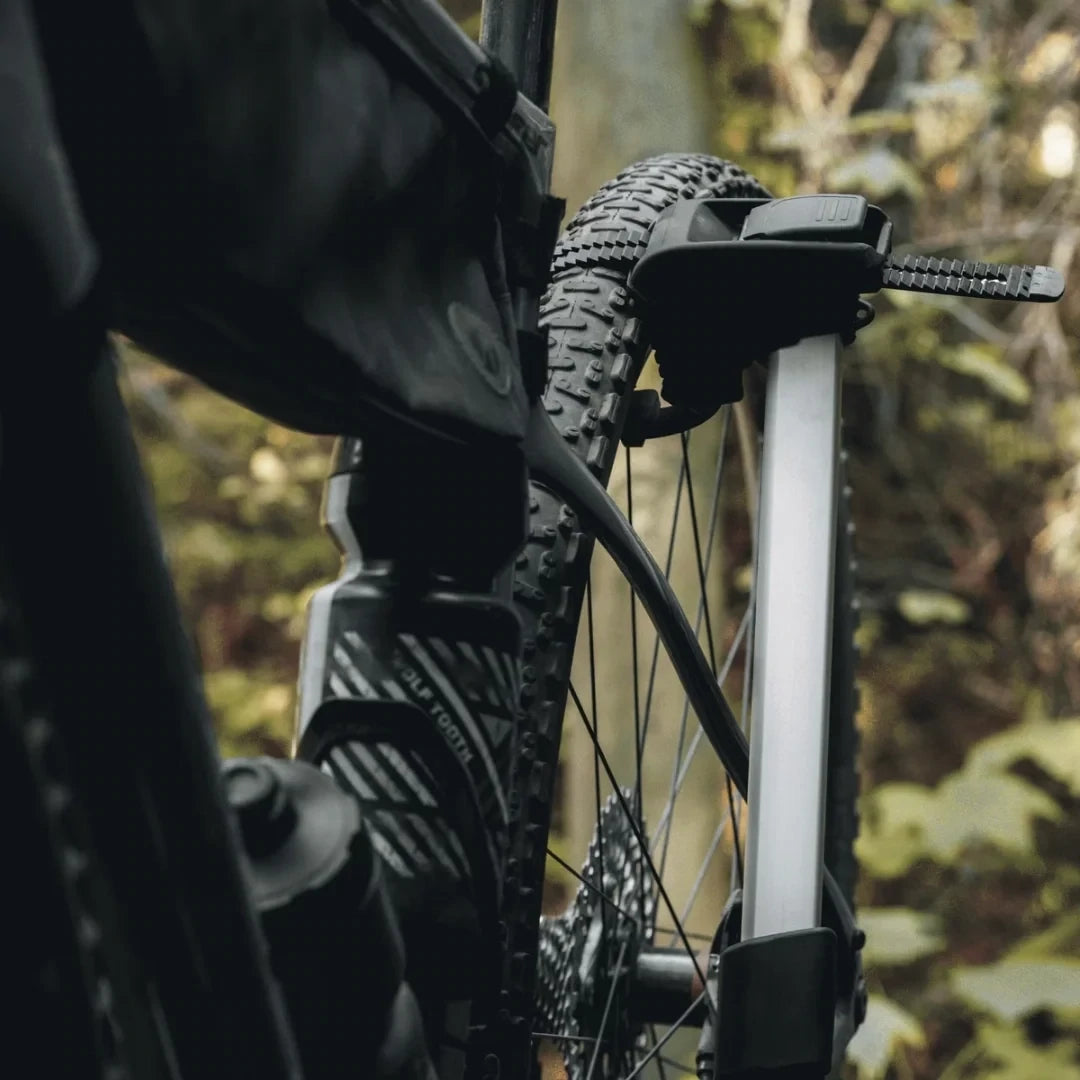 Close-up of bike tire mounted on the rack arm in wooded area