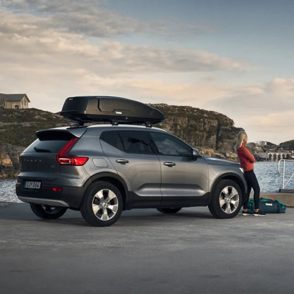 SUV parked near a scenic coastal area, equipped with a Thule Force XT Sport cargo box.