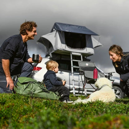 Family sitting near SUV with rooftop tent deployed