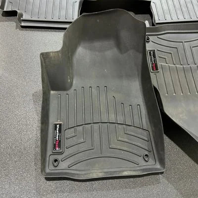 Black car floor mats with a brand logo on a gray surface