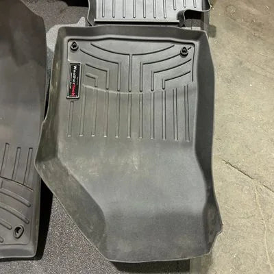 Gray car floor mat with a brand logo on a concrete surface