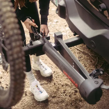 Person adjusting a bike with a close-up of the bike's frame and tires on a dirt path.