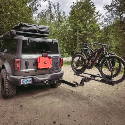 Gray SUV with a bike on a rack in a forest setting
