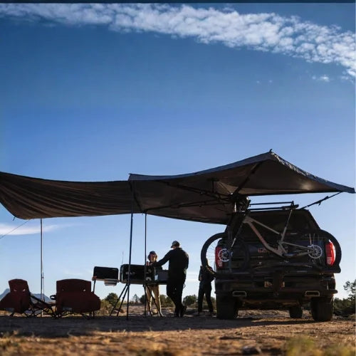 Yakima OverNOut 270 freestanding rooftop awning creating shaded campsite shelter beside overlanding pickup truck, ideal for camping, outdoor cooking, and adventure travel across Canada.