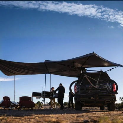 Yakima OverNOut 270 freestanding rooftop awning creating shaded campsite shelter beside overlanding pickup truck, ideal for camping, outdoor cooking, and adventure travel across Canada.