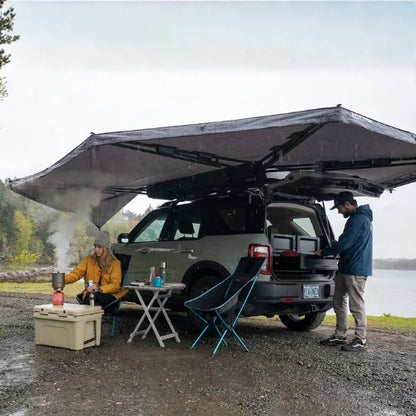 Yakima OverNOut 270 rooftop awning deployed over SUV campsite in Canada, providing freestanding shade and shelter for overlanding cooking and outdoor camping.