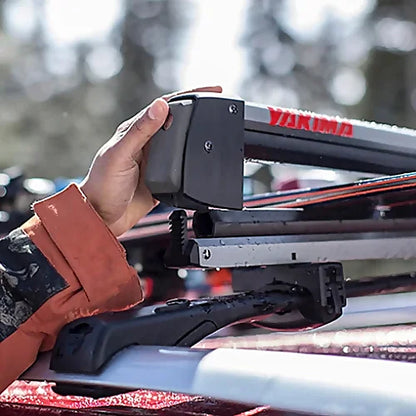 Skier securing gear on Yakima FreshTrack ski rack in snowy mountain setting.