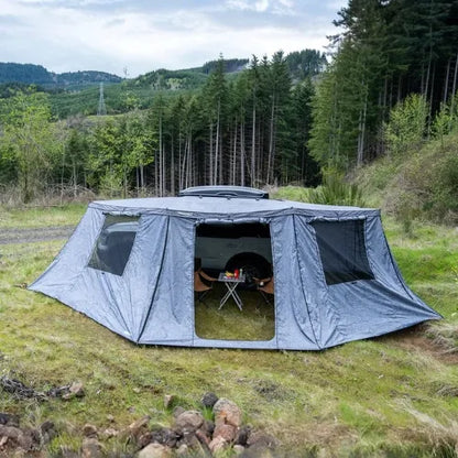 Gray tent set up outdoors with a forest in the background