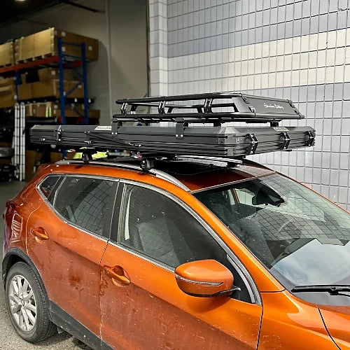 Orange SUV with Adventure Outdoors rooftop tent and black crossbars mounted securely