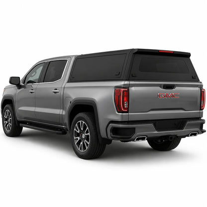 A silver GMC pickup truck with a black hardtop canopy over the bed, shown from a rear three-quarter angle on a white studio background.