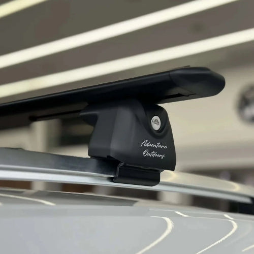 AetherBars AO universal roof rack system installed on raised rails with anti-theft locking foot and low-profile crossbar