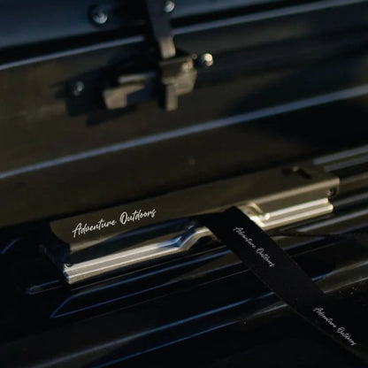 Interior view of Branch AO roof box showing Quick-Clamp mounting system and tie-down strap for secure cargo storage