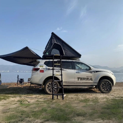 2025 Cocoon AO Clamshell Rooftop Tent setup on Nissan Terra with awning extended at lakeside campsite