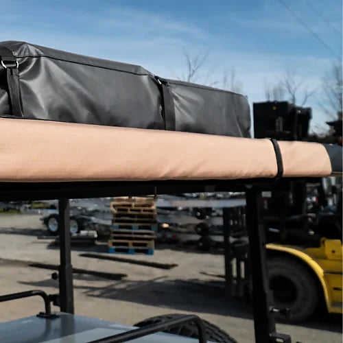 Dog House vehicle awning with black PVC cover and rolled desert tan fabric
