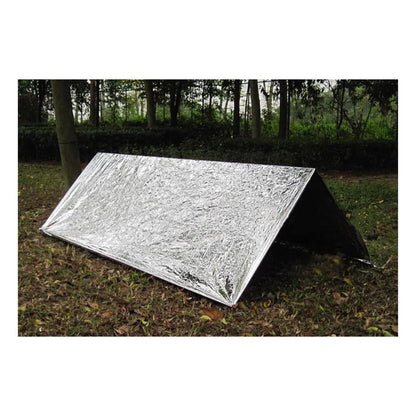 Emergency thermal blanket set up as a reflective survival shelter in a forest
