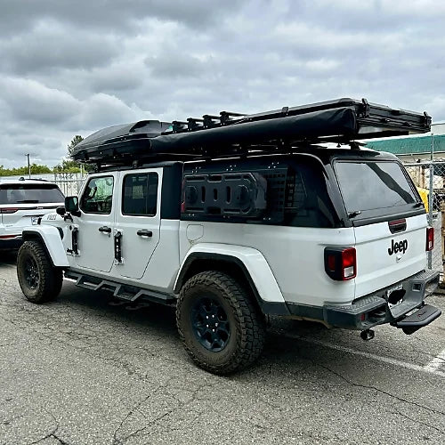 Jeep Gladiator off-road camping setup with roof bars, awning, and gear platform