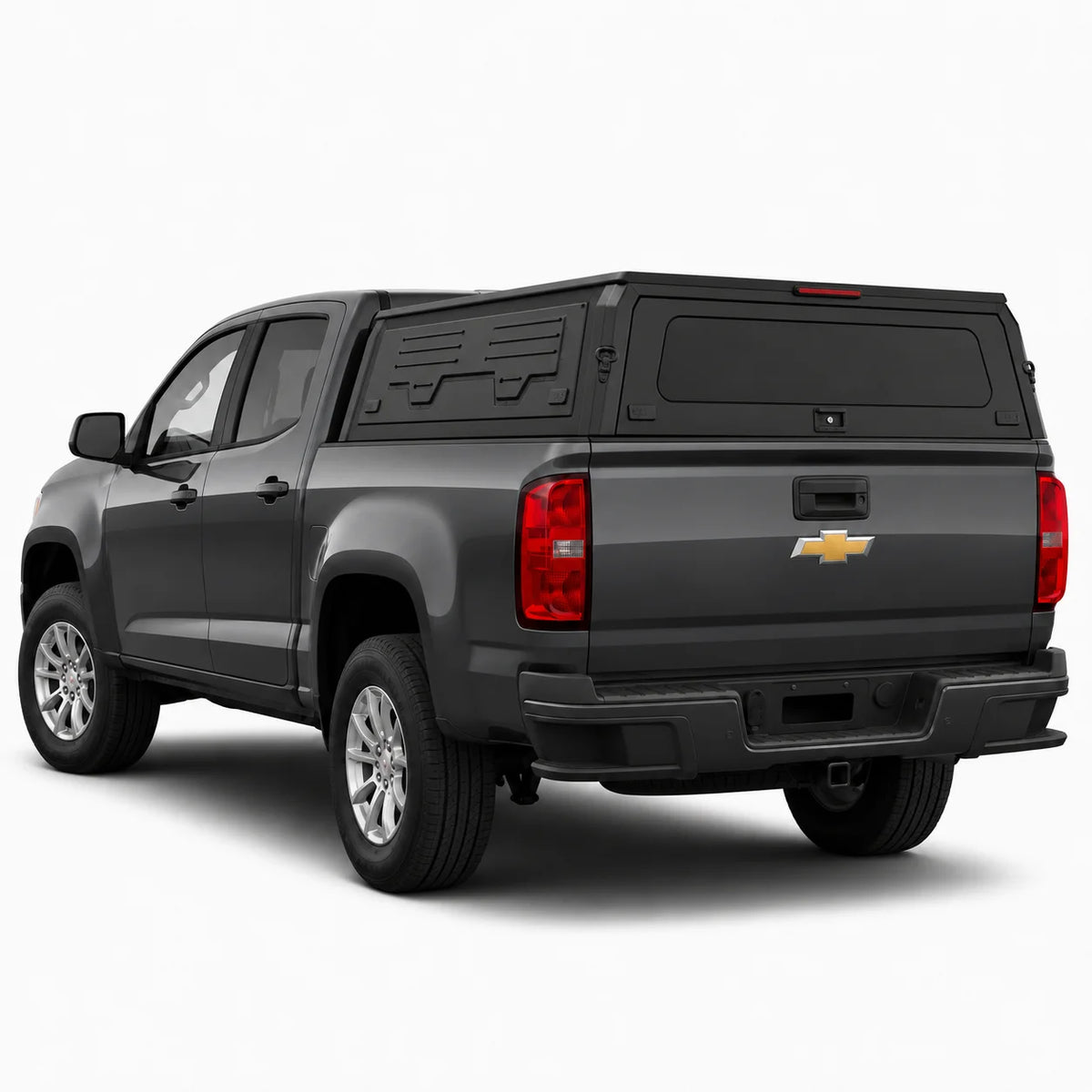 A dark gray Chevrolet pickup truck with a black hardtop canopy over the bed, shown from a rear three-quarter angle on a light gray studio background.