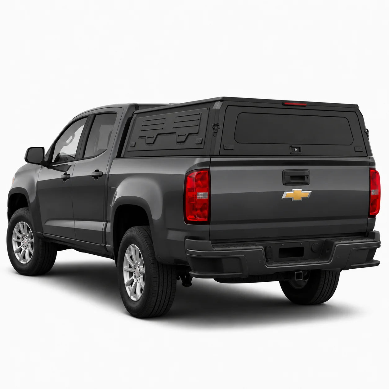 A dark gray Chevrolet pickup truck with a black hardtop canopy over the bed, shown from a rear three-quarter angle on a light gray studio background.